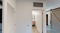 This single-floor space showcases a clean, contemporary design defined by polished concrete floors that flow consistently throughout. The open-concept living area benefits from a generous bank of black-framed windows, flooding the space with natural light and offering views of the surrounding streetscape.

The kitchen is thoughtfully designed with two-tone cabinetry—light wood lower cabinets paired with matte gray upper cabinets—complemented by a white subway tile backsplash, quartz countertops, and a full suite of stainless steel appliances including a gas range, built-in microwave, dishwasher, and side-by-side refrigerator. A butcher block bar-height table with hairpin legs adds a modern accent.

The bedrooms are bright and well-proportioned, each featuring recessed lighting, sliding or hinged closet access, and individual windows. A spacious walk-in closet offers multi-tier wire shelving and hanging rods along all walls for ample storage.

Two bathrooms serve the unit: one features a floating wood vanity, large mirror with medicine cabinets, white tile surround, and a combined tub-shower, while the second offers a walk-in tiled shower stall with polished floors.
