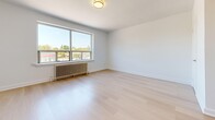 Located at 31 Clearview in Toronto's M6M neighbourhood, this efficiently designed unit offers a practical and clean layout across a single floor, comprising a living room, kitchen, bathroom, and hallway. Light-toned hardwood flooring runs throughout the space, lending a consistent, modern aesthetic that enhances the sense of openness.

The living room is the most prominent area, featuring a large picture window that frames outdoor greenery and neighbourhood views, flooding the room with natural light. A classic cast-iron radiator sits beneath the window, providing character alongside its functional purpose. The walls are finished in crisp white, complementing the airy feel of the room.

The kitchen is compact and efficiently arranged, featuring white cabinetry, a subway tile backsplash, a stainless steel stove, and a refrigerator. The streamlined galley-style layout makes practical use of the available space.

The bathroom is finished in an all-white palette, with classic hexagonal penny tile flooring, a mirrored medicine cabinet, open wall shelving, a white vanity with under-cabinet storage, and a full bathtub with shower. White square wall tiles add a timeless, clean look.

A hallway connects the main rooms, providing a clear and functional flow throughout the unit. Overall, the space presents a bright, clean, and well-maintained interior suited for comfortable everyday living.