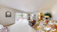 Located at 5743 Kingfish Dr in Lutz, Florida, this single-floor residence offers a straightforward and functional layout designed for comfortable everyday living. The open living and dining area serves as the central hub of the home, featuring plush wall-to-wall carpeting, a textured ceiling, and a large sliding glass door fitted with vertical blinds that floods the space with natural light and provides direct access to an outdoor patio. The seamless flow between the living and dining areas creates a spacious, cohesive feel throughout.

The kitchen is efficiently arranged with warm wood-toned cabinetry extending to the upper walls for ample storage, a double-basin sink, electric range, and a full-size refrigerator. Its compact footprint makes practical use of every available surface.

The bedroom is generously sized, featuring soft carpeting and its own sliding glass door with vertical blinds that opens to the patio, offering natural light and outdoor views of surrounding greenery. The open connection between the bedroom and living area enhances the sense of space throughout the home.

The bathroom features light tile flooring, a long vanity with an integrated sink, and a separate water closet, providing a clean and functional layout. Overall, this home presents a bright, easy-to-navigate single-level floor plan well-suited to the Lutz, FL lifestyle.