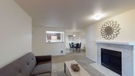 This single-floor residence offers a thoughtfully organized layout with distinct living, dining, kitchen, and sleeping areas. The living room serves as a central gathering space, highlighted by a tile-surround fireplace, soft wall-to-wall carpeting, and a sliding glass door that allows natural light to flow in while providing access to the outdoors. A pass-through window connects the living area to the kitchen, enhancing the open feel of the shared spaces. The kitchen is equipped with dark espresso cabinetry, stone-look countertops, a white range, and durable tile flooring that extends into the adjacent dining area. The dining space is defined by a pendant light overhead and offers a comfortable setting for everyday meals. The bedrooms are carpeted and feature baseboard heating along with windows that bring in natural light and outdoor views. The primary bedroom provides ample space and a calm, neutral aesthetic. The bathroom includes a vanity with stone-look countertops, a mirrored medicine cabinet, and brushed nickel fixtures. A dedicated laundry area with a full-size washer and dryer adds a practical convenience. Throughout, the neutral color palette and consistent finishes create a cohesive and functional living environment.