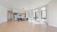 Located at 421 N Pennsylvania St in the heart of downtown Indianapolis, this contemporary 2-bedroom, 1-bathroom residence offers a thoughtfully designed open floor plan with high-end finishes throughout. The expansive open-concept kitchen and living area is anchored by large floor-to-ceiling windows that flood the space with natural light while framing views of the surrounding urban skyline. The kitchen features two-tone cabinetry, a spacious waterfall-edge island with an integrated sink and matte black fixtures, stainless steel appliances including a French door refrigerator and built-in microwave, and pendant lighting overhead. Light wood-style flooring runs throughout the main living areas, enhancing the bright, airy atmosphere. The generously sized primary bedroom is carpeted and bathed in natural light through a dramatic wall of floor-to-ceiling windows overlooking the cityscape. The second bedroom also benefits from tall windows and light wood flooring. The bathroom is elegantly appointed with marble-style tile flooring, a wide floating wood vanity, a large mirror, matte black fixtures, and a separate tub/shower combination. Additional conveniences include a dedicated laundry room, utility room, and multiple closets for ample storage.