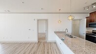 Located at 11613 Vista Terrace Way in Knoxville, Tennessee, this single-floor residence offers a thoughtfully designed open-concept layout with a clean, contemporary aesthetic throughout. The kitchen serves as a central highlight, anchored by a large island with a granite countertop and double stainless steel sink, illuminated by stylish pendant lighting. Rich, warm-toned cabinetry provides generous storage and pairs well with stainless steel appliances, including a refrigerator, range, and microwave. Light wood-style flooring flows through the main living areas, complementing the bright white walls and creating an airy, cohesive feel. The living area is generously proportioned, featuring a ceiling fan and large windows that invite abundant natural light and views of the surrounding Knoxville landscape. The bedrooms are well-sized, with plush carpeting in select rooms and ample natural light from multiple windows. The bathroom showcases a granite-topped vanity with dual sinks, rich cabinetry, and backlit mirrors, adding a refined touch. Additional utility space includes a dedicated laundry area with wire shelving and hookups. The overall ambiance is fresh, modern, and move-in ready, offering comfortable and stylish single-floor living.