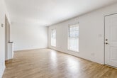 This well-designed 2-bedroom, 1-bathroom unit offers a clean, modern aesthetic throughout its single-floor layout. Light wood-style flooring runs seamlessly through every room, creating a warm and cohesive feel. The spacious living room is bathed in natural light from dual windows fitted with blinds, and opens directly to the kitchen via a half-wall pass-through, enhancing the sense of openness between spaces.

The kitchen is thoughtfully appointed with gray shaker-style cabinetry, granite-look countertops, a classic white subway tile backsplash, and a full suite of stainless steel appliances including a refrigerator, gas range, microwave, and dishwasher. A hallway connects the main living areas to the two bedrooms and shared bathroom, with a closet providing additional storage.

Both bedrooms feature the same light flooring, white walls, and windows that invite natural light. The primary bedroom is generously sized and includes a ceiling fan. The second bedroom also features a ceiling fan for added comfort.

The bathroom is finished with a granite-top vanity with shaker-style cabinetry, a large mirror, and a tub-shower combination surrounded by white subway tile, maintaining the cohesive design palette found throughout the unit.