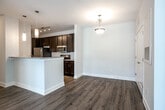 Located at 12509 Crown Park Ct in Charlotte, NC, this single-floor residence offers a clean, contemporary design with a neutral color palette throughout. The open living area is finished with warm wood-look flooring and flows seamlessly toward the entryway, which is accented by elegant pendant lighting. A ceiling fan adds comfort to the living space, and natural light filters in through multiple windows fitted with blinds.

The kitchen is a functional highlight, featuring rich dark espresso cabinetry paired with granite-look countertops, a classic white subway tile backsplash, and a full suite of stainless steel appliances including a refrigerator, range, and microwave. Track lighting illuminates the space, and a breakfast bar provides additional counter space and casual seating potential.

The bedrooms are carpeted in plush neutral tones, each benefiting from generous natural light through large windows with blinds and ceiling fan fixtures. The bathrooms are consistently appointed with dark wood vanities, granite-look countertops, large mirrors with brushed nickel vanity lighting, and full soaking tub and shower combinations finished with wood-look flooring. The cohesive finishes and thoughtful layout make this Charlotte residence a comfortable and well-designed single-level home.