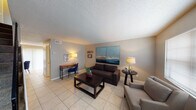This two-floor home offers a well-organized layout with comfortable living spaces across multiple rooms. The living area is finished with light tile flooring and features a textured ceiling, neutral gray walls, and ample room for seating. A large two-panel ocean-inspired canvas anchors the main wall, complemented by warm lamp lighting and a built-in desk nook — ideal for working from home. The kitchen is efficiently designed with white cabinetry, dark speckled countertops, a stainless steel sink, and a full range with overhead ventilation, all set atop light tile flooring. The bedroom is generously sized with soft wall-to-wall carpeting, a ceiling fan, textured walls, and a bright window that allows natural light to filter in, creating a calm and restful atmosphere. A small seating area by the window adds a functional touch. The home includes two bathrooms: a half bath with a single vanity and toilet, and a full bathroom featuring a tub/shower combo with tile surround, a vanity with stone-look countertop, and tile flooring. Throughout the space, thoughtful decorative touches, including motivational wall art and coastal-themed accents, contribute to a warm and lived-in ambiance.