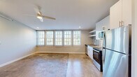 This 2-bedroom, 1-bathroom unit in Memphis, Tennessee offers a compelling mix of industrial loft character and modern finishes. Polished concrete floors run throughout the space, lending an urban aesthetic that pairs well with the clean, neutral color palette on the walls. The open-concept kitchen and living area forms the heart of the unit, highlighted by a row of large, grid-pane windows fitted with horizontal blinds that flood the space with natural light and offer leafy outdoor views. A ceiling fan with integrated lighting adds comfort and functionality overhead, while exposed ductwork contributes to the loft-inspired design.

The kitchen is well-equipped with stainless steel appliances — including a refrigerator, range, microwave, and dishwasher — white cabinetry, open shelving, and a stainless sink. The primary bedroom is generously proportioned, featuring multiple large windows that continue the theme of abundant natural light. A second bedroom with a sloped ceiling provides a cozy, loft-like feel with its own closet access. The bathroom is finished with white subway tile in a glass-enclosed walk-in shower, hexagonal mosaic tile flooring, and clean, contemporary fixtures. A dedicated closet and hallway round out this thoughtfully laid-out unit.