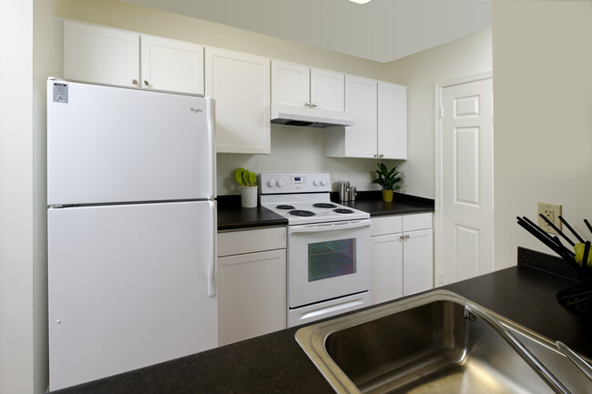 Kitchen with white appliances, white cabinetry and black countertops - eaves Fairfax City