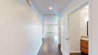 This thoughtfully designed 2-bedroom, 2-bathroom residence offers a comfortable and functional single-floor layout. Dark hardwood flooring flows throughout the main living areas and hallway, providing a warm contrast to the crisp white walls and recessed lighting overhead. The open living room is bright and spacious, with multiple windows and a balcony door that frame panoramic views of the surrounding cityscape and distant hills, filling the room with natural light.

The kitchen features warm-toned wooden cabinetry, granite countertops, and a full suite of stainless steel appliances, including a side-by-side refrigerator with ice maker, electric range, and built-in microwave. A window above the counter brings in additional natural light.

Both bedrooms are carpeted for comfort and include built-in closets with wooden shelving. The generously sized primary bedroom offers ample space, while the second bedroom is equally well-proportioned. Each of the two bathrooms is finished with rich wood cabinetry, granite countertops, a large framed mirror, and a tiled shower-tub combination enclosed by a sleek glass door. A central hallway connects all rooms efficiently, completing the well-organized floor plan.