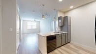 This well-designed 2-bedroom, 2-bathroom residence in Austin, Texas offers a thoughtful single-floor layout with modern finishes and a bright, welcoming atmosphere. The open-concept kitchen and living area serves as the heart of the home, anchored by a peninsula with granite countertops, an undermount sink, and pendant lighting with gold accents. Gray cabinetry, black appliances, and a built-in dishwasher complete the kitchen's contemporary aesthetic, while light wood-style flooring flows seamlessly throughout the entire space.

The living area extends naturally from the kitchen, benefiting from a ceiling fan and a window that invites natural light. Both bedrooms are comfortably sized, each featuring ceiling fans, light wood-style flooring, and windows with blinds that frame outdoor views. The primary bedroom connects to a private bathroom equipped with granite-topped vanity, built-in shelving, and a dedicated walk-in closet. The second bathroom features matching granite countertops, dark cabinetry, and a full tub-shower combination. Two closets provide ample storage throughout the home, rounding out this practical and polished Austin residence.