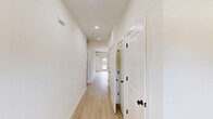 This thoughtfully designed one-bedroom, one-bathroom residence at 365 Ridge Rd in Dayton, NJ offers a bright and modern living experience. Light wood-look flooring runs throughout the entire unit, creating a clean, cohesive aesthetic complemented by crisp white walls and abundant natural light from multiple windows.

The open-concept kitchen and living area forms the heart of the unit. The kitchen is outfitted with rich warm-toned wood cabinetry, white quartz countertops, stainless steel appliances including a gas range, microwave, and refrigerator, and recessed lighting overhead. A peninsula counter provides additional workspace and casual seating. A wall-mounted mini-split system ensures efficient climate control in both the kitchen and living areas.

The living room is generously sized, featuring a glass-paned exterior door that brings in natural light and outdoor views. Two hallways connect the main living space to the private areas of the unit, providing a practical and efficient layout.

The bedroom is a comfortable retreat with its own wall-mounted mini-split unit, a built-in closet, and direct access to the full bathroom. The bathroom is a standout feature, showcasing large-format marble-look tile surrounding a deep soaking tub, matte black fixtures, and a wood-accented vanity with white countertop — a refined finishing touch to this well-appointed home.