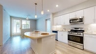 Located at 3411 Grande Vista Pkwy in Riverside, CA, this single-floor home offers three bedrooms and two bathrooms with a clean, contemporary design. The kitchen is a standout feature, showcasing crisp white cabinetry, light stone countertops, a curved breakfast island with pendant lighting, and a full suite of stainless steel appliances including a gas range, dishwasher, microwave, and French door refrigerator. Light wood-style flooring runs throughout the kitchen and living areas, contributing to a bright and cohesive aesthetic. The living room receives natural light through sizable windows and is equipped with a ceiling fan for added comfort. The primary bedroom is a well-proportioned retreat with light wood-style flooring, direct outdoor access via a glass door, and a ceiling fan. Secondary bedrooms feature neutral carpet, large windows with blinds that invite natural light, and ceiling fans. The bathrooms are finished with white cabinetry, stone-tone countertops, large mirrors, and a tub/shower combination. Two closets provide practical storage throughout the home. The overall ambiance is modern, clean, and move-in ready, making it a comfortable and functional residence in the heart of Riverside.