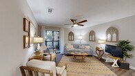 Located at 800 Runaway Bay Lane in Mount Pleasant, South Carolina, this well-appointed two-bedroom, two-bathroom residence offers a thoughtfully designed single-floor layout. The open-concept living, dining, and kitchen area serves as the heart of the home, with hardwood-style flooring flowing throughout. The living room features crown molding, a ceiling fan, and a sliding glass door that opens to a private balcony, filling the space with natural light and offering pleasant outdoor views. The galley-style kitchen is outfitted with white cabinetry, granite countertops, stainless steel appliances, and a deep undermount sink. The adjacent dining area provides a welcoming space for entertaining. The primary bedroom is a comfortable retreat with soft carpet, ample closet space, and an en-suite bathroom featuring a granite-topped vanity, white cabinetry, and a tiled tub/shower combination. The second bedroom is similarly well-sized with natural light and its own closet access. A second full bathroom mirrors the same refined finishes. Additional conveniences include a dedicated laundry area, utility room, and multiple closets throughout. The neutral color palette and coastal-inspired accents lend the space a calm, inviting ambiance.