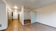 Located in Seattle's vibrant South Lake Union neighborhood, this 1-bedroom, 1-bathroom unit at 1201 Mercer St offers a thoughtfully designed modern layout across a single floor. Light wood-tone flooring runs throughout, creating a warm and cohesive aesthetic from room to room.

The open-concept living and dining area flows naturally from the kitchen, maximizing the sense of space. A distinctive frosted glass sliding panel separates the bedroom from the main living area, allowing light to pass through while providing privacy — a sleek architectural detail that adds character to the interior.

The kitchen is a standout feature, outfitted with two-tone cabinetry combining crisp white upper cabinets with textured gray lower cabinets. A subway tile backsplash in muted gray tones complements the white countertops, while black appliances including a gas range, dishwasher, microwave, and refrigerator complete the contemporary look. Ample cabinet storage extends floor to ceiling.

The bedroom is an intimate, well-defined space served by a ceiling fan and includes access to two closets for practical storage. Clean white walls throughout the unit contribute to a bright and airy ambiance. The unit's efficient, well-considered layout makes excellent use of every square foot, offering a comfortable and stylish urban living experience.