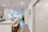 Located at 1 Henry Circle in the coastal community of Flagler Beach, Florida, this well-appointed single-story home offers three bedrooms, two bathrooms, and a thoughtfully designed layout. The open-concept living, dining, and kitchen area forms the heart of the home, bathed in natural light and finished with durable wood-look flooring throughout. The kitchen is a standout feature, showcasing granite countertops, a large center island with bar seating, contemporary light-wood cabinetry, stainless steel appliances including a refrigerator, range, and microwave, and ample built-in shelving for storage. Pendant lighting adds a stylish touch above the island. The living room is bright and welcoming, with a ceiling fan and glass door that opens to a balcony, offering outdoor views. The three bedrooms feature plush carpeting and ceiling fans, with the primary bedroom offering generous proportions and closet space. The bathrooms are finished with granite vanity tops, wood-look tile flooring, and a soaking tub with shower. A dedicated in-unit laundry room houses a full-size washer and dryer with overhead shelving. Five closets throughout provide abundant storage, rounding out this clean, modern coastal home.