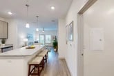 Located at 1 Henry Circle in the coastal community of Flagler Beach, Florida, this well-appointed single-story home offers three bedrooms, two bathrooms, and a thoughtfully designed layout. The open-concept living, dining, and kitchen area forms the heart of the home, bathed in natural light and finished with durable wood-look flooring throughout. The kitchen is a standout feature, showcasing granite countertops, a large center island with bar seating, contemporary light-wood cabinetry, stainless steel appliances including a refrigerator, range, and microwave, and ample built-in shelving for storage. Pendant lighting adds a stylish touch above the island. The living room is bright and welcoming, with a ceiling fan and glass door that opens to a balcony, offering outdoor views. The three bedrooms feature plush carpeting and ceiling fans, with the primary bedroom offering generous proportions and closet space. The bathrooms are finished with granite vanity tops, wood-look tile flooring, and a soaking tub with shower. A dedicated in-unit laundry room houses a full-size washer and dryer with overhead shelving. Five closets throughout provide abundant storage, rounding out this clean, modern coastal home.