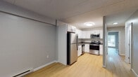 This single-floor unit offers a practical and well-appointed layout designed for comfortable everyday living. Light wood laminate flooring runs consistently throughout the space, creating a cohesive and easy-to-maintain aesthetic. Neutral gray walls provide a versatile backdrop across all rooms.

The kitchen is equipped with a full suite of stainless steel appliances, including a refrigerator, electric range, and over-the-range microwave. White shaker-style cabinetry lines the walls, offering generous storage, while dark countertops provide contrast. The kitchen connects openly to the living area, which features baseboard heating and a smooth flow into adjacent spaces.

Two bedrooms provide comfortable living quarters, each featuring windows that allow natural light and views of the surrounding greenery. One bedroom includes access to a dedicated in-unit laundry closet with a stacked washer and dryer, as well as a spacious walk-in closet nearby.

Two bathrooms serve the unit — one featuring a full soaking tub with an integrated surround and built-in shelving, and the other a compact stand-up shower stall. Both bathrooms are finished with clean white fixtures and wood-tone flooring, maintaining the unit's consistent and functional design throughout.