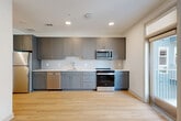 Located at 1450 Morrison Road in Denver, CO, this well-appointed one-bedroom, one-bathroom residence offers a thoughtfully designed single-floor layout. The open-concept living, dining, and kitchen area serves as the heart of the home, bathed in natural light from large windows. The kitchen is outfitted with sleek gray shaker-style cabinetry, white subway tile backsplash, light quartz countertops, and a full suite of stainless steel appliances including a range, microwave, dishwasher, and refrigerator. Light hardwood flooring flows throughout the main living areas, adding warmth and continuity to the space. A well-proportioned hallway with recessed lighting connects the living areas to the private quarters, lined with multiple closets for generous storage. The bedroom features plush carpeting, a ceiling fan, and a sliding double-door closet. The bathroom is finished with large-format marble-look tile surrounding the soaking tub and shower, complemented by a gray vanity and hardwood flooring. Additional functional spaces include a dedicated laundry area and utility room. Clean white walls and recessed lighting throughout create a bright, modern ambiance ideal for everyday living.