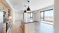 Located in Denver's vibrant Five Points neighborhood, this modern 2-bedroom, 2-bathroom residence offers a thoughtfully designed open-concept layout. The combined kitchen and living area serves as the heart of the home, featuring light wood cabinetry, a bold dark-topped island with pendant lighting, subway tile backsplash, stainless steel appliances, and hardwood-style flooring that extends throughout the main living spaces. Large floor-to-ceiling windows flood the living area with natural light and frame striking city skyline views.

Each bedroom is generously proportioned, with plush carpeting, ceiling fans, and large windows that continue to bring in natural light and urban vistas. Both bedrooms are complemented by dedicated closets equipped with built-in shelving and hanging rods for ample storage. The primary bathroom showcases warm wood-tone cabinetry, a dark stone countertop, gold-accented fixtures, and direct access to a walk-in closet. The second bathroom features a soaking tub with dramatic dark tile surround. Throughout the residence, crisp white panel doors with matte black hardware add a cohesive modern touch, while a connecting hallway ties the layout together seamlessly.