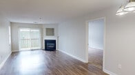 Located at 9 Forest Glen Cir in Middletown, CT, this single-floor, 2-bedroom, 2-bathroom residence offers a well-organized layout with a clean, neutral aesthetic throughout. The living room serves as the heart of the home, featuring gleaming hardwood-style flooring, a classic fireplace with a white mantel, and a sliding glass door that fills the space with natural light and provides outdoor access. A built-in niche above the fireplace adds a subtle architectural detail. The entry and dining area continue the hardwood-style flooring, accented by a hanging pendant light fixture that adds a touch of warmth. Both bedrooms are finished with plush carpeting and include windows that bring in natural light. The spacious primary bedroom features direct access to one of the two bathrooms, offering added privacy and convenience, and includes a closet. The second bedroom also includes a closet with organizational features. Both bathrooms are finished with tile flooring and white cabinetry. One bathroom includes a full tub/shower combination, while the other features a vanity with a lighted mirror. A hallway connects the main living areas to the bedrooms, and a dedicated closet provides additional storage. The overall palette of soft whites and warm neutrals creates a bright, clean, and move-in-ready atmosphere.
