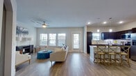 This single-story residence is built around an open-concept floor plan that seamlessly connects the living, dining, and kitchen areas. The living room is bright and welcoming, featuring wood-look flooring, a ceiling fan, and multiple windows that invite generous natural light. An arched hallway leads to additional rooms, adding a subtle architectural detail to the space.

The kitchen is a functional centerpiece, showcasing dark espresso cabinetry, stainless steel appliances, a subway tile backsplash, and a large granite-topped island with bar seating. Pendant lighting above the island adds both style and practicality. Adjacent to the living area, the dining nook offers an intimate setting, accented by tall framed mirrors that enhance the sense of space.

The primary bedroom is carpeted and comfortably sized, with a ceiling fan and a window providing natural light. It connects to a well-appointed en-suite bathroom featuring a dual-sink vanity with granite countertops, dark wood cabinetry, and a large framed mirror. A walk-in closet with multi-rail storage completes the suite. A secondary carpeted room provides flexibility as a home office or additional bedroom. Throughout, neutral tones and consistent finishes create a cohesive and modern ambiance.