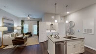 This thoughtfully designed 2-bedroom, 2-bathroom residence in Panama City Beach, Florida delivers a polished, modern living experience across a single floor. The open-concept kitchen serves as the heart of the home, featuring white shaker cabinetry, a subway tile backsplash, quartz-style countertops, stainless steel appliances including a refrigerator with ice maker, electric range, and built-in microwave, and a center island with pendant lighting and seating. Dark hardwood-style flooring flows throughout the main living areas, creating a warm, cohesive aesthetic. The living room offers generous space, elevated ceilings, a ceiling fan, and large windows with natural light. Both bedrooms are well-sized, each with windows, soft neutral tones, and dark flooring. Both bathrooms are outfitted with soaking tub and shower combinations tiled in a sleek gray subway pattern. One bathroom connects to a walk-in closet with built-in shelving. A dedicated in-unit laundry area with a full-size washer and dryer is conveniently accessible from the main living space. The overall design balances coastal-inspired warmth with contemporary finishes, making it a comfortable and functional home in a desirable Florida Gulf Coast location.