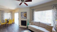 This single-story residence offers a thoughtfully designed layout with consistent finishes and a warm, neutral color palette throughout. The living room serves as the central gathering space, anchored by a tile-surround fireplace and outfitted with a ceiling fan overhead. Large windows dressed with patterned curtains and vertical blinds allow ample natural light to filter in, creating a bright and inviting atmosphere. A sliding glass door in the adjacent dining area provides direct outdoor access and additional light, complemented by a pendant light above the dining table.

The galley-style kitchen features white cabinetry, dark granite-style countertops, and stainless and black appliances, including a range, microwave, and refrigerator, with wood-style flooring tying the space together.

The bedrooms offer a comfortable retreat with plush carpeting, ceiling fans, and generous closet space, including mirrored sliding closet doors in one room. Each bedroom benefits from multiple windows that bring in natural light.

The bathrooms are well-equipped with white cabinetry, dark countertops, undermount sinks, and tub-shower combinations. Wood-style flooring extends through the bathrooms, maintaining a cohesive design throughout the entire residence.