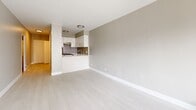 This well-appointed studio in Montréal's vibrant landscape offers a thoughtfully organized single-floor layout comprising a living area, a full bathroom, and a closet. The interior is defined by a clean, modern aesthetic, with light-toned luxury vinyl flooring flowing throughout and crisp white walls that maximize the sense of brightness and openness.

The main living area is spacious relative to the studio format, benefiting from a large window and a door that opens onto a balcony, providing urban views of the surrounding Montréal skyline and filling the space with abundant natural light. Baseboard heating units are integrated along the walls, ensuring year-round comfort.

The kitchen is seamlessly incorporated into the living space via a peninsula-style counter, offering a functional open-concept arrangement. White cabinetry, a tiled backsplash, built-in appliances including an oven, and a stainless steel sink come together to create a practical and visually cohesive cooking area.

A hallway connects the main living space to the bathroom and closet. The bathroom features a clean, contemporary design with a combination bathtub and shower lined in white subway tile, a light wood-toned vanity with a white countertop and undermount sink, polished chrome fixtures, and a large mirror. The dedicated closet provides convenient, organized storage.

Overall, the studio presents a bright, modern, and efficiently designed living environment in a prime Montréal location.