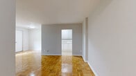 This well-proportioned three-bedroom, one-bathroom unit at 1284 Danforth Road offers a comfortable and practical layout across a single floor. The space is unified throughout by warm-toned parquet wood flooring in a classic basket-weave pattern, lending a timeless character to every room.

The living room is generously sized, featuring neutral grey walls, clean white baseboards, and a large window that fills the space with natural light and frames lush, tree-lined views. A radiator beneath the window provides efficient heating. The open feel of the room is enhanced by its bright, airy palette.

Each of the three bedrooms continues the parquet flooring theme. Two of the bedrooms feature windows overlooking greenery, paired with radiators, creating bright and comfortable retreats. The primary bedroom includes a double-door closet, offering practical built-in storage. A third bedroom also features a double closet and connects conveniently to the hallway.

The bathroom is finished with full-height pale yellow ceramic tile surrounding a full-sized soaking tub and shower combination, complemented by chrome fixtures and a wall-mounted medicine cabinet.

A central hallway connects all rooms efficiently, contributing to the unit's functional flow. The neutral tones, natural light, and consistent flooring throughout create a cohesive and inviting living environment.
