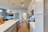 Located at 138 Rosewick Corner Place in La Plata, Maryland, this well-appointed 3-bedroom, 3-bathroom residence offers a thoughtfully designed single-floor layout. The open-concept living, dining, and kitchen area serves as the heart of the home, featuring warm wood-look flooring, recessed and pendant lighting, and large glass doors that flood the space with natural light and provide direct access to a private patio with outdoor views. The kitchen is highlighted by gray shaker-style cabinetry, white quartz countertops, a center island with bar seating, a subway tile backsplash, and a full suite of stainless steel appliances. The bedrooms are generously sized, with the primary bedroom offering wide windows with outdoor views and ample closet space supported by built-in wire shelving systems. The bathrooms are clean and modern, featuring white tile tub-shower surrounds, gray vanities, and quartz counters. A dedicated laundry room includes a full-size washer and dryer with overhead wire shelving. The entrance hall connects all areas efficiently, and four closets throughout provide excellent storage. The residence combines contemporary finishes with practical functionality throughout.