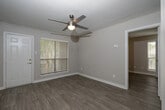 Located at 15215 Blue Ash Dr in Houston, TX, this single-floor unit offers a clean, modern interior designed for comfortable everyday living. The open-concept layout connects the kitchen and living area seamlessly, creating a cohesive and functional living space throughout.

The kitchen is well-appointed with white shaker-style cabinetry, light quartz countertops, and a full suite of stainless steel appliances including an electric range, over-the-range microwave, and refrigerator. A peninsula with a double-basin stainless steel sink extends into the main living area, making it ideal for casual dining or meal prep. Adjacent to the kitchen, a set of louvered bi-fold doors opens to a generously sized pantry fitted with multi-tier wire shelving, offering abundant storage.

The living area is bright and airy, benefiting from multiple windows dressed with white horizontal blinds that invite natural light. A ceiling fan with an integrated light fixture adds both comfort and functionality to this space.

The bathroom features a tub-shower combo with white tile surround, a single-sink vanity with white cabinetry, and wood-style flooring that carries throughout the unit, providing a consistent and cohesive aesthetic. The neutral, warm-gray wall tones paired with white trim and fixtures give the entire space a fresh, move-in-ready feel.