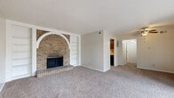 Located in Liberty, Missouri, this single-floor, three-bedroom, one-bathroom unit offers a practical and comfortable layout across a cozy footprint. The living room serves as the centerpiece of the home, anchored by a striking full-brick fireplace wall featuring a distinctive white-painted arched alcove and flanking built-in shelving — a standout architectural detail that adds character to the space. Plush carpet flows throughout the living and bedroom areas, while textured ceilings add a classic finish overhead. Large sliding glass doors in the living area fill the space with natural light and provide direct access to a private fenced outdoor area, enhancing the sense of openness. A secondary entry door is also conveniently located nearby. The galley-style kitchen features warm wood cabinetry lining both walls, light countertops, a gas range, refrigerator, and wood-look flooring, offering efficient use of space. The three bedrooms are carpeted and well-proportioned, with at least one featuring a window with outdoor views. Two closets provide dedicated storage, one of which includes built-in adjustable shelving. The full bathroom includes a tiled shower-tub combination, a vanity, and wood-look flooring, completing this functional and inviting layout.