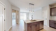 Located at 26109 Chaise St in Ballston Spa, NY, this well-appointed 2-bedroom, 1-bathroom single-floor home offers a thoughtfully designed layout with modern finishes throughout. The open-concept kitchen and living area serves as the heart of the home, anchored by a sizeable center island with a quartz countertop, an undermount sink, and a sleek matte black pull-down faucet. Pendant lighting with glass jar fixtures hangs above the island, adding a contemporary touch. The kitchen features rich, medium-toned shaker cabinetry, a herringbone tile backsplash, stainless steel appliances including a French door refrigerator, range, and microwave, providing both style and functionality. Light hardwood-style flooring flows seamlessly throughout the entire home, enhancing the bright and airy atmosphere. The living room is bathed in natural light through large sliding glass doors with vertical blinds that open to an outdoor view. Both bedrooms are calm and neutral in tone, with large windows allowing generous sunlight. The full bathroom is well-equipped with a dual-sink vanity featuring matching shaker cabinetry, matte black fixtures, a large mirror, and a full soaking tub with shower. Clean white walls and recessed lighting complete the modern, move-in-ready aesthetic of this Ballston Spa home.