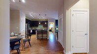 Located at 5550 Bexley Way NW in Concord, NC, this single-floor residence offers a well-designed open-concept layout with stylish finishes throughout. The kitchen is a standout feature, showcasing dark espresso cabinetry, granite countertops, a large central island with bar seating, and a full suite of stainless steel appliances including a refrigerator, microwave, range, and dishwasher. Warm hardwood flooring and yellow-green accent walls give the kitchen an energetic yet inviting atmosphere. The open flow connects seamlessly to the dining and living areas, where hardwood floors continue and French doors lead to an outdoor space, allowing natural light to fill the room. The living area offers a comfortable, functional layout with a ceiling fan overhead. The bedrooms feature plush carpeting and tray ceilings, with large windows that invite natural light. The primary bedroom is particularly well-appointed with ample space and views to the main living area. Two full bathrooms are finished with dark vanity cabinetry, full tub-shower combinations, and wood-look flooring. A dedicated in-unit laundry room with full-size washer and dryer adds everyday convenience. Overall, the space balances modern finishes with a warm, livable aesthetic.