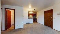 Located in Wauwatosa, Wisconsin, this single-floor home offers a functional and comfortable layout with a clean, straightforward design throughout. The open living area features neutral carpet flooring and crisp white walls, creating a bright and welcoming atmosphere. A sliding glass door fills the space with natural light and provides direct access to an outdoor balcony area with views of mature trees. The kitchen is well-appointed with rich wood cabinetry, dark granite-style countertops, a stone tile backsplash, and a full suite of stainless steel appliances including a dishwasher, range, and over-the-range microwave. Durable tile flooring completes the kitchen area. The bedrooms are generously sized, carpeted, and feature baseboard heating, wood-trimmed doors, and ample closet space. Two bathrooms serve the home — one full bath with a tub-shower combination, tile flooring, and a dark wood vanity, and a second half bath with a stone-topped vanity and framed mirror. Warm wood trim accents are consistent throughout the home, lending a cohesive and classic feel. The overall layout is efficient and well-connected, making this Wauwatosa residence a practical and comfortable place to call home.