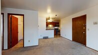 Located in Wauwatosa, Wisconsin, this single-floor home offers a functional and comfortable layout with a clean, straightforward design throughout. The open living area features neutral carpet flooring and crisp white walls, creating a bright and welcoming atmosphere. A sliding glass door fills the space with natural light and provides direct access to an outdoor balcony area with views of mature trees. The kitchen is well-appointed with rich wood cabinetry, dark granite-style countertops, a stone tile backsplash, and a full suite of stainless steel appliances including a dishwasher, range, and over-the-range microwave. Durable tile flooring completes the kitchen area. The bedrooms are generously sized, carpeted, and feature baseboard heating, wood-trimmed doors, and ample closet space. Two bathrooms serve the home — one full bath with a tub-shower combination, tile flooring, and a dark wood vanity, and a second half bath with a stone-topped vanity and framed mirror. Warm wood trim accents are consistent throughout the home, lending a cohesive and classic feel. The overall layout is efficient and well-connected, making this Wauwatosa residence a practical and comfortable place to call home.