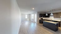 This single-floor unit offers a well-designed, open-concept layout that seamlessly connects the living area and kitchen. The living space features light wood-style luxury vinyl plank flooring, neutral gray walls, and recessed lighting, creating a bright and airy atmosphere. Multiple windows and a glass balcony door allow abundant natural light and provide views of the surrounding neighborhood's greenery and streetscape.

The kitchen is outfitted with dark espresso cabinetry, granite countertops, a center island with additional seating and counter space, stainless steel appliances including a refrigerator, and a classic white tile backsplash. Pendant lighting and track lighting add both function and style.

The two bedrooms are carpeted for comfort and each features a ceiling fan, generous windows, and ample natural light. One bedroom includes large sliding glass doors that open to a private balcony with neighborhood views.

The unit includes two bathrooms. The primary bathroom offers a long double-sink vanity with granite counters, dark cabinetry, wood-look flooring, and a glass-enclosed walk-in shower. The secondary bathroom features a similar vanity style alongside a soaking tub with a tiled surround.