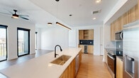 This contemporary 920 square foot apartment in Atlanta offers a harmonious blend of style and functionality. The open-concept design creates a seamless flow between the living areas, maximizing space and natural light. Floor-to-ceiling windows dominate the main living area, flooding the space with sunlight and providing stunning cityscape views.

The kitchen is a chef's dream, featuring sleek wooden cabinetry, stainless steel appliances, and a striking blue backsplash. A large island with a built-in sink serves as both a prep area and casual dining spot. The living room is spacious and bright, with ample room for entertaining or relaxing.

The bedroom, measuring 200 square feet, offers a private retreat with large windows and a modern ceiling fan. The bathroom is a study in elegance, with a double vanity, large mirrors, and a glass-enclosed shower. Light-colored tile flooring and ample lighting create a spa-like atmosphere.

Throughout the apartment, warm wood-tone flooring contrasts beautifully with the crisp white walls, creating a cohesive and inviting ambiance. The well-designed closet space features multiple hanging rods and shelves for optimal organization. Modern ceiling fans and recessed lighting add both style and functionality to this thoughtfully designed urban home.
