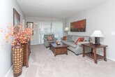 Located at 1295 Walton Blvd in Rochester Hills, Michigan, this single-floor residence offers a thoughtfully designed layout that balances open communal areas with comfortable private spaces. The living room serves as a welcoming centerpiece, featuring neutral-toned walls, carpet flooring, and large sliding glass doors with vertical blinds that allow generous natural light to filter in. The space flows seamlessly into the dining area, which is anchored by a ceiling fan and connects directly to the galley-style kitchen. The kitchen is efficiently organized with white cabinetry lining both sides, dark countertops, white appliances including an electric range and refrigerator, and hardwood-style flooring that adds warmth and contrast.

The bedrooms are carpeted and well-proportioned, each featuring windows with vertical blinds that frame outdoor views of the surrounding greenery. The primary bedroom is particularly notable for its dual-exposure windows and access to a spacious walk-in closet fitted with built-in shelving on both sides. The adjoining bathroom features a wide vanity with dark countertops, white cabinetry below, and a large mirror. The overall ambiance throughout is clean, neutral, and functional, making it a practical and comfortable living space.