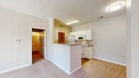 This single-floor residence offers a practical and comfortable layout designed for everyday living. The entry foyer welcomes you with tile flooring that transitions into soft, neutral-toned carpeting throughout the main living areas and bedrooms. The spacious living room is a standout, featuring a fireplace with a clean white mantel and a large sliding glass door fitted with vertical blinds, providing access to the outdoors and allowing generous natural light to fill the space.

The kitchen is designed for efficiency, featuring white cabinetry with gold hardware, a full suite of white appliances including a refrigerator, electric range, and over-the-range microwave, as well as a functional peninsula that opens toward the living area. Light wood-tone flooring runs through the kitchen, adding warmth to the space. Ample counter space and upper and lower cabinets provide generous storage throughout.

The bedrooms are carpeted and comfortably sized, with windows that bring in natural light. The bathroom includes a vanity with white cabinetry, a wall-mounted mirror, and wood-look flooring. A walk-in closet with built-in shelving is conveniently located adjacent to the bathroom. A dedicated laundry room houses a full-sized washer and dryer and includes overhead shelving, adding further functionality to this well-rounded home.