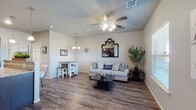 This single-story unit offers a well-organized layout that balances open communal spaces with a comfortable private retreat. The living area serves as the heart of the unit, featuring durable wood-look plank flooring, a ceiling fan with light fixture, and a window that admits natural light while offering outward views. Neutral wall tones provide a versatile backdrop throughout the space.

The kitchen is outfitted with dark espresso cabinetry, granite-style countertops, and black appliances, including a refrigerator and dishwasher. A peninsula with seating for two extends into the living area, enhancing the open-concept flow and creating a functional casual dining space. Pendant lighting above the peninsula adds focused illumination and visual interest. The transition between the kitchen and living room is seamless, making the combined area well-suited for everyday living.

The bedroom offers plush carpeting underfoot, a ceiling fan, and a window dressed with light curtains that allow natural light in. The bathroom includes a full tub-shower combination with a clean white surround, dark cabinetry for storage, and wood-look tile flooring, maintaining a cohesive design aesthetic across the unit.