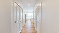 Unit 513 at 140 Rantoul Street in Beverly, Massachusetts offers a thoughtfully designed single-floor layout with a clean, contemporary aesthetic. Light hardwood flooring runs throughout the entire unit, complementing the bright white walls and creating a warm, cohesive atmosphere.

The open-concept kitchen is a standout feature, equipped with stainless steel appliances including a refrigerator, range, microwave, and dishwasher. White cabinetry extends to the ceiling, providing ample storage, while a large central island with a white countertop offers additional workspace and casual seating. Recessed and pendant lighting complete the kitchen's modern look.

The living area is generously proportioned, bathed in natural light from oversized windows and a sliding glass door that opens to a private balcony with views of the surrounding Beverly neighborhood. Additional bedrooms also benefit from large windows that invite natural light.

A well-appointed hallway connects the main living areas to the private spaces, lined with clean white panel doors and a louvered closet. The bathroom features a glass-enclosed walk-in shower, a white vanity with an undermount sink, and matching hardwood-style flooring. A walk-in closet with wire shelving provides practical storage. The unit's modern finishes and abundant natural light make it a bright and functional living space.