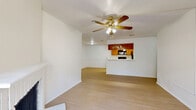This single-floor, 2-bedroom, 2-bathroom residence offers a practical and comfortable layout with consistent light wood-style flooring flowing throughout every room. The open living area is anchored by a classic brick fireplace and a ceiling fan with integrated lighting, creating a warm and inviting atmosphere. A sliding glass door fills the space with natural light and provides direct access to an outdoor patio area. The kitchen is designed in a galley style, featuring warm wood cabinetry, white countertops, black appliances including a range, refrigerator, and dishwasher, and a pass-through window that connects to the living area. The spacious primary bedroom includes its own ceiling fan and direct access to a full bathroom equipped with warm wood vanity cabinetry, a large mirror, and a tiled shower-tub combination. The second bedroom also features a ceiling fan and a window for natural light. A second full bathroom serves guests and additional occupants. The home also includes multiple closets for ample storage, a dedicated laundry area, a utility room, and a hallway connecting the private sleeping quarters to the main living spaces. The clean, neutral color palette and consistent finishes contribute to a cohesive and move-in-ready ambiance throughout.
