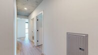 Located in the heart of downtown Phoenix, this contemporary 3-bedroom, 3-bathroom residence showcases an striking urban aesthetic defined by exposed concrete ceilings, light hardwood flooring, and an abundance of natural light. The open-concept kitchen and living area serves as the social hub of the home, featuring a sleek waterfall-edge island with an undermount sink, white cabinetry, stainless steel appliances, and globe pendant lighting that adds a warm, modern touch. Floor-to-ceiling windows throughout the living spaces frame sweeping views of the Phoenix skyline, filling each room with natural light and a vibrant sense of the city below. The generously sized primary bedroom enjoys panoramic city views through expansive glazing, exposed concrete ceiling details, and a ceiling fan, while each bedroom includes its own dedicated closet. The bathrooms are finished to a high standard, featuring large-format tile flooring, floor-to-ceiling white subway tile, dark wood vanities with undermount sinks, bold matte black fixtures, and oversized mirrors. A central hallway connects all rooms efficiently, and the overall palette of white walls, concrete, and warm wood tones creates a cohesive, contemporary urban living environment.