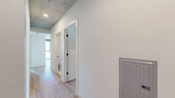 Located in the heart of downtown Phoenix, this contemporary 3-bedroom, 3-bathroom residence showcases an striking urban aesthetic defined by exposed concrete ceilings, light hardwood flooring, and an abundance of natural light. The open-concept kitchen and living area serves as the social hub of the home, featuring a sleek waterfall-edge island with an undermount sink, white cabinetry, stainless steel appliances, and globe pendant lighting that adds a warm, modern touch. Floor-to-ceiling windows throughout the living spaces frame sweeping views of the Phoenix skyline, filling each room with natural light and a vibrant sense of the city below. The generously sized primary bedroom enjoys panoramic city views through expansive glazing, exposed concrete ceiling details, and a ceiling fan, while each bedroom includes its own dedicated closet. The bathrooms are finished to a high standard, featuring large-format tile flooring, floor-to-ceiling white subway tile, dark wood vanities with undermount sinks, bold matte black fixtures, and oversized mirrors. A central hallway connects all rooms efficiently, and the overall palette of white walls, concrete, and warm wood tones creates a cohesive, contemporary urban living environment.