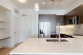 Located at 1500 Westbranch Drive in McLean, Virginia, this well-designed one-bedroom, one-bathroom residence offers a thoughtful open-concept layout that seamlessly connects the living, dining, and kitchen areas into a single cohesive space. Light wood-tone flooring runs throughout, lending warmth and continuity across the floor plan.

The kitchen is a standout feature, showcasing rich dark wood cabinetry that extends to the ceiling for ample storage, a neutral tile backsplash, and a full suite of stainless steel appliances including a French door refrigerator, electric range, microwave, and dishwasher. A peninsula with a crisp white quartz countertop and undermount sink doubles as a breakfast bar, illuminated by elegant pendant lighting and complemented by a track lighting system overhead.

The bedroom is bright and airy, benefiting from a large window that invites natural light and offers exterior views. A ceiling fan adds comfort, while two closets provide generous storage. The bathroom features large-format tile flooring, a floating dark wood vanity with a white countertop, and a clean, minimalist aesthetic that carries through the hallway. A dedicated in-unit laundry area adds everyday convenience, completing this efficiently designed McLean residence.