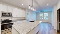 This well-appointed 2-bedroom, 3-bathroom single-story residence offers a thoughtfully designed open-concept layout that maximizes every square foot. The kitchen serves as the centerpiece of the living space, showcasing a large granite-topped island with an undermount sink and elegant pendant lighting overhead. Crisp white shaker cabinetry extends to the ceiling, providing generous storage, while stainless steel appliances — including a refrigerator, range, and built-in microwave — complete the modern aesthetic. Light wood-look flooring flows seamlessly from the kitchen into the adjoining living area, which is brightened by natural light from a dual-pane window and kept comfortable by a ceiling fan. The two bedrooms offer a calm, neutral palette with plush carpeting and window views of surrounding greenery. The primary bedroom includes an en-suite bathroom featuring granite countertops, white cabinetry, and a glass-enclosed shower, along with direct access to a walk-in closet fitted with wire shelving. Two additional closets throughout the unit provide ample storage. With three full bathrooms, a clean modern design, and quality finishes at every turn, this residence delivers a comfortable and functional living experience.