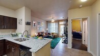 This thoughtfully designed two-bedroom, two-bathroom residence in Oxford, Mississippi delivers a comfortable and functional single-floor layout. The open-concept living and kitchen area serves as the heart of the home, where light wood-style flooring flows throughout. The kitchen is well-appointed with dark espresso cabinetry, granite countertops, stainless steel refrigerator, black appliances including a range and built-in microwave, and a peninsula with sink that opens directly to the living area. The living room benefits from large windows and a glass door that invite abundant natural light, with a ceiling fan overhead adding to the airy feel. Both bedrooms feature bold accent walls, plush carpeting, and generous closets. One bedroom includes a built-in desk and shelving, offering a practical study nook. The two bathrooms are finished with matching granite-top vanities and dark cabinetry; one includes a shower-tub combo. A dedicated in-unit laundry closet with a full-size washer and dryer adds everyday convenience. The overall ambiance is warm and functional, making this residence a practical and comfortable home in Oxford.