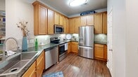 Located at 1207 Legacy Oaks Pl in Asheville, NC, this single-floor, 2-bedroom, 2-bathroom home offers a thoughtfully designed layout with comfortable living across a generous footprint. Hardwood-style flooring flows through the main living areas, complementing a warm, cohesive aesthetic throughout.

The kitchen is a functional highlight, featuring rich honey-toned cabinetry, dark granite countertops, a tile backsplash, and a full suite of stainless steel appliances including a French door refrigerator, range, microwave, and dishwasher. A pantry provides additional storage. The adjacent combined dining and living area is bright and open, with track and recessed lighting, crown molding accents, and a bold blue accent wall that adds striking character to the living space.

The primary bedroom offers a comfortable, carpeted retreat with a ceiling fan and natural light from large windows. It is served by a spacious walk-in closet with wire shelving and a full bathroom featuring warm wood cabinetry, granite countertops, and a tub/shower combination. The second bedroom is equally well-appointed with plush carpeting, a ceiling fan, and generous natural light. A hallway, dedicated laundry area, and four closets round out the practical and well-organized floor plan.