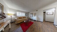 This single-floor unit in Wichita, Kansas offers an efficiently organized layout that maximizes its compact footprint. The combined living and dining area serves as the heart of the space, featuring rich, dark hardwood-style flooring, a textured ceiling, and a large window with vertical blinds that admits natural light. The living area provides enough room for comfortable seating and a coffee table, while a defined dining nook accommodates a round table with seating for four, positioned adjacent to the kitchen.

The kitchen is a functional galley-style space equipped with a range, dishwasher, and tile countertops, with light tile flooring extending underfoot. A hallway connects the main living areas to the private bedroom, which features wall-to-wall carpet, a window with blinds, and sufficient space for a full-sized bed and additional furnishings. A dedicated closet provides practical built-in storage. The single bathroom includes a vanity with a marble-patterned countertop, medicine cabinet with mirror, and tile flooring. Throughout the unit, neutral wall tones and consistent finishes create a cohesive, understated aesthetic.