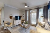 Located at 100 Cavalier Crossing in Stonecrest, GA, this 2-bedroom, 2-bathroom residence offers a thoughtfully designed single-floor layout that balances comfort and functionality. The living room welcomes with crown molding, wood-look flooring, a ceiling fan, and large windows fitted with blinds and drape panels that invite natural light while maintaining privacy. The adjacent dining area makes a bold statement with deep navy accent walls, classic wainscoting, and elegant crown molding. The kitchen is outfitted with white cabinetry, granite countertops, a grey subway tile backsplash, and black appliances, flowing seamlessly into the dining and living spaces. The primary bedroom features plush carpeting and a striking navy accent wall, complemented by a walk-in closet with wire shelving. The second bedroom offers similar comfort and storage. Both bathrooms include granite vanities, with one showcasing a tub-shower combination adorned with a classic black-and-white diamond tile border. A dedicated in-unit laundry room with a full-size washer and dryer adds everyday convenience. The hallway connects all areas with cohesive flooring and a clean, modern aesthetic throughout.